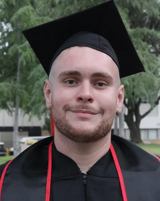 Manuel Marin III at his CSUN graduation, in cap and gown, smiling.